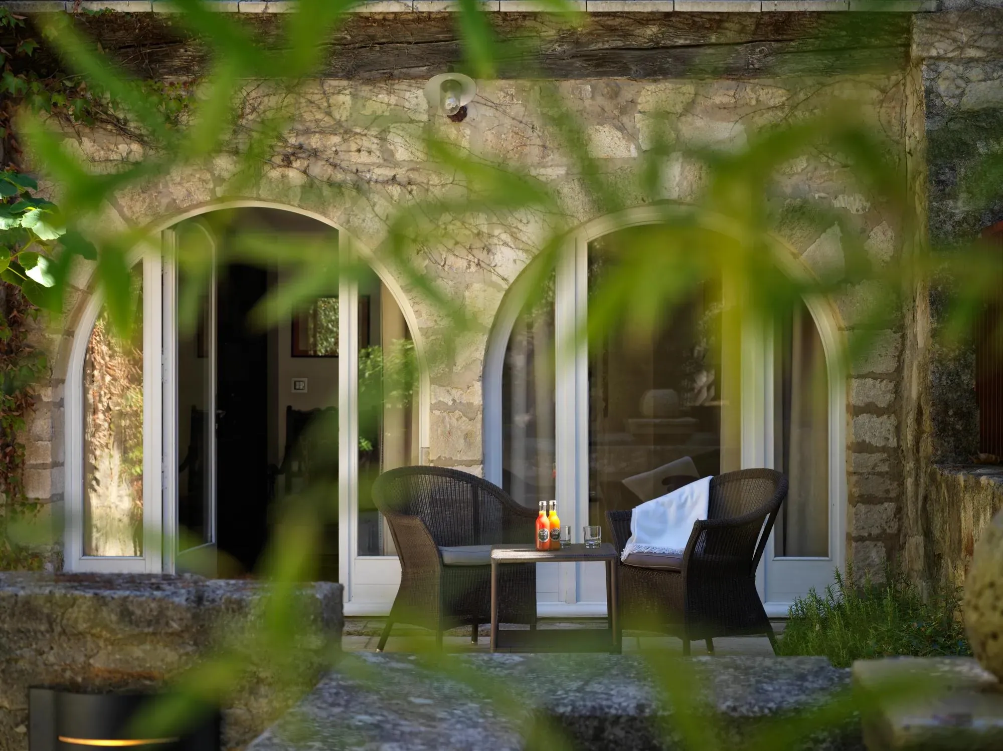Les arcades de pierre et la terrasse aux fauteuils en rotin