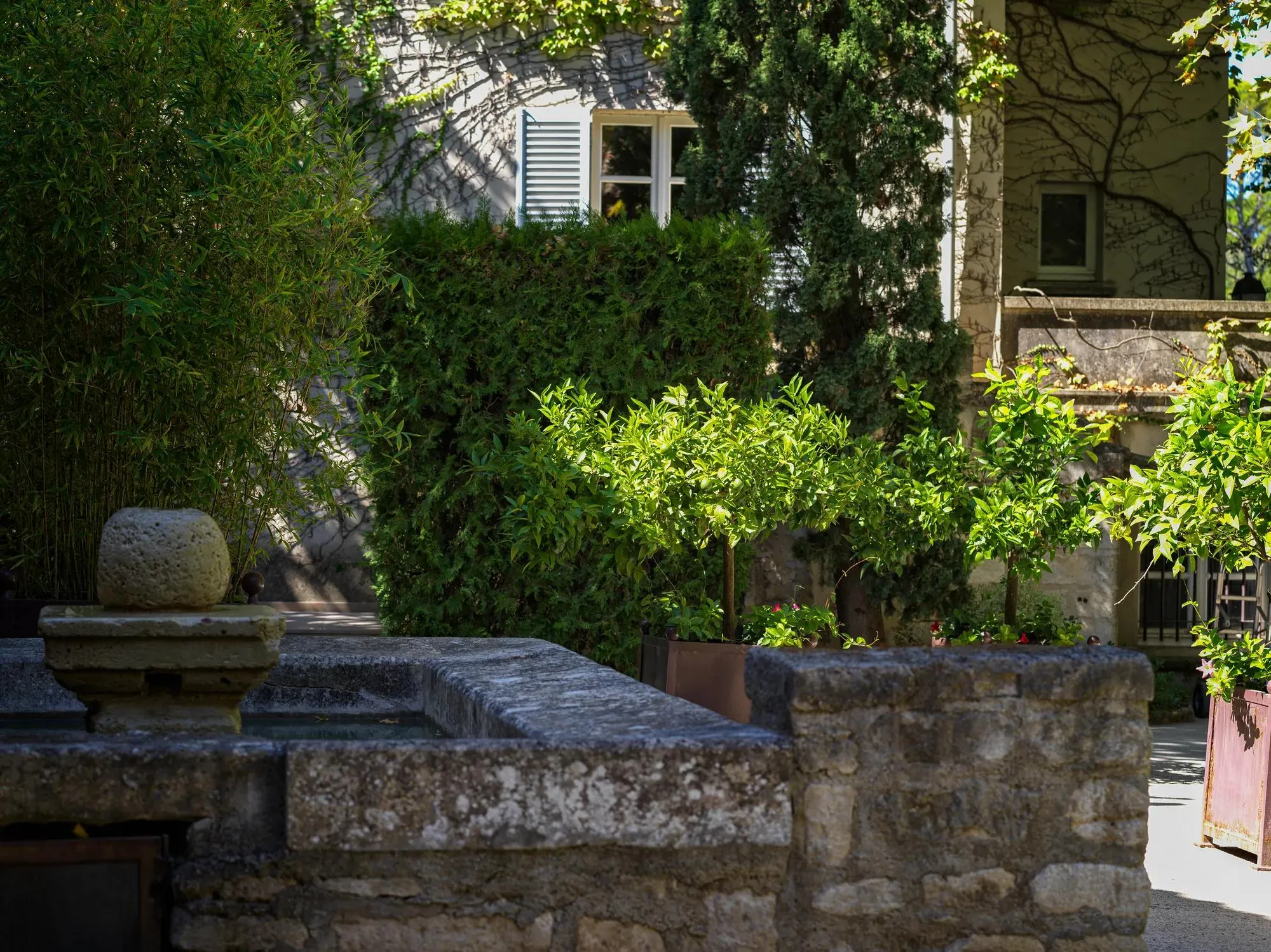 Les bâtisses de pierre du Prieuré et leurs volets, autour du jardin