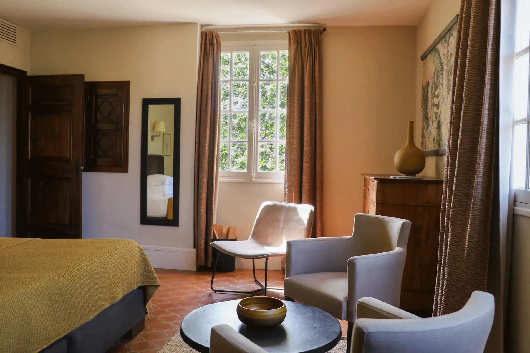 Chambre avec fauteuils gris et fenêtre sur le jardin