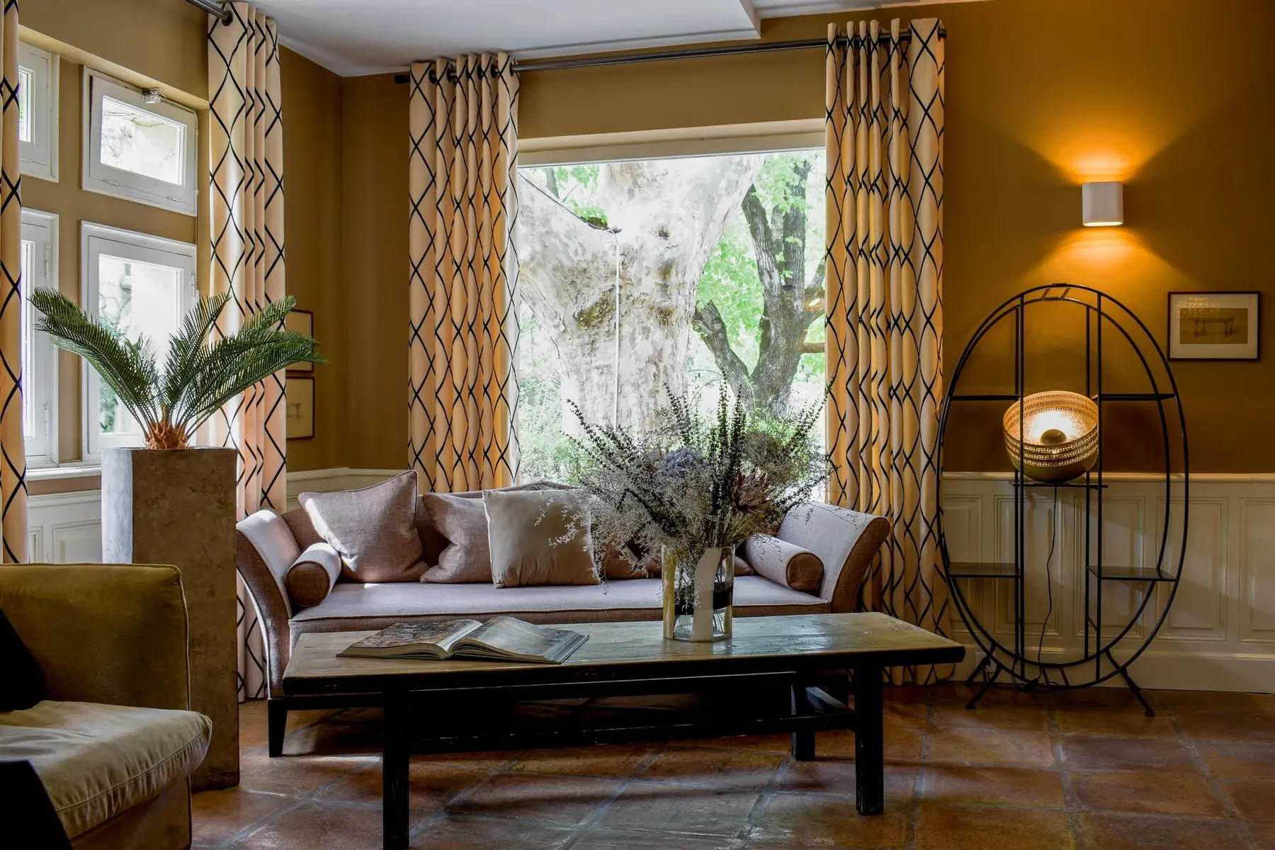 Salon aux tomettes, canapé et rideaux à motifs